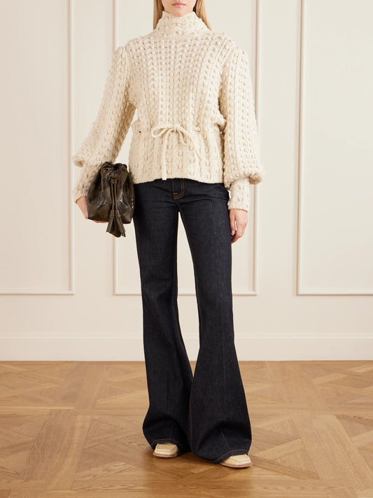 Image of a model wearing Outerwear. Product name - Valiant Tie-detailed Knitted Wool Turtleneck Sweater in Cream colour by brand - Zimmermann