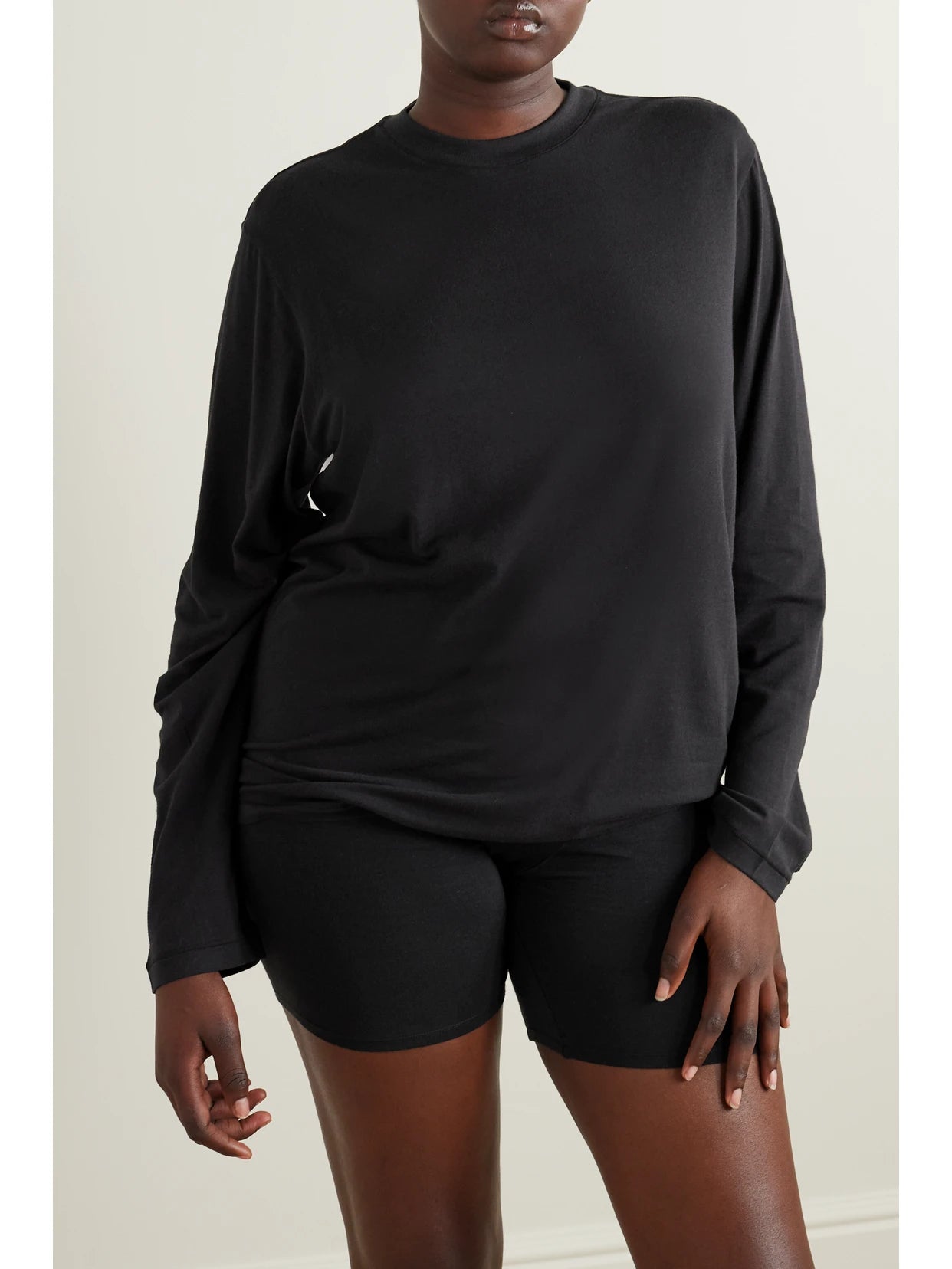Image of a model wearing Tops. Product name - Boyfriend Stretch-modal And Cotton-blend Jersey T-shirt - Onyx in Black colour by brand - SKIMS