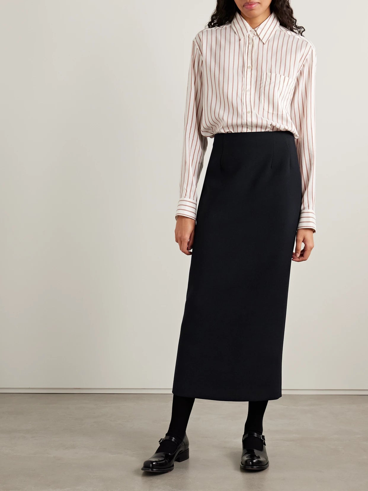 Image of a model wearing Skirts. Product name - Talor Wool Midi Skirt in Navy colour by brand - The Row
