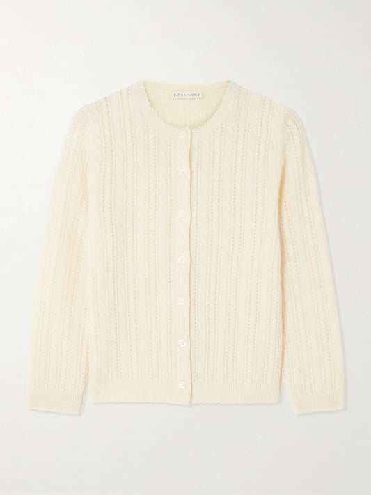 Image of a model wearing Outerwear. Product name - Danae Cropped Cable-knit Cashmere Cardigan in Cream colour by brand - DÔEN