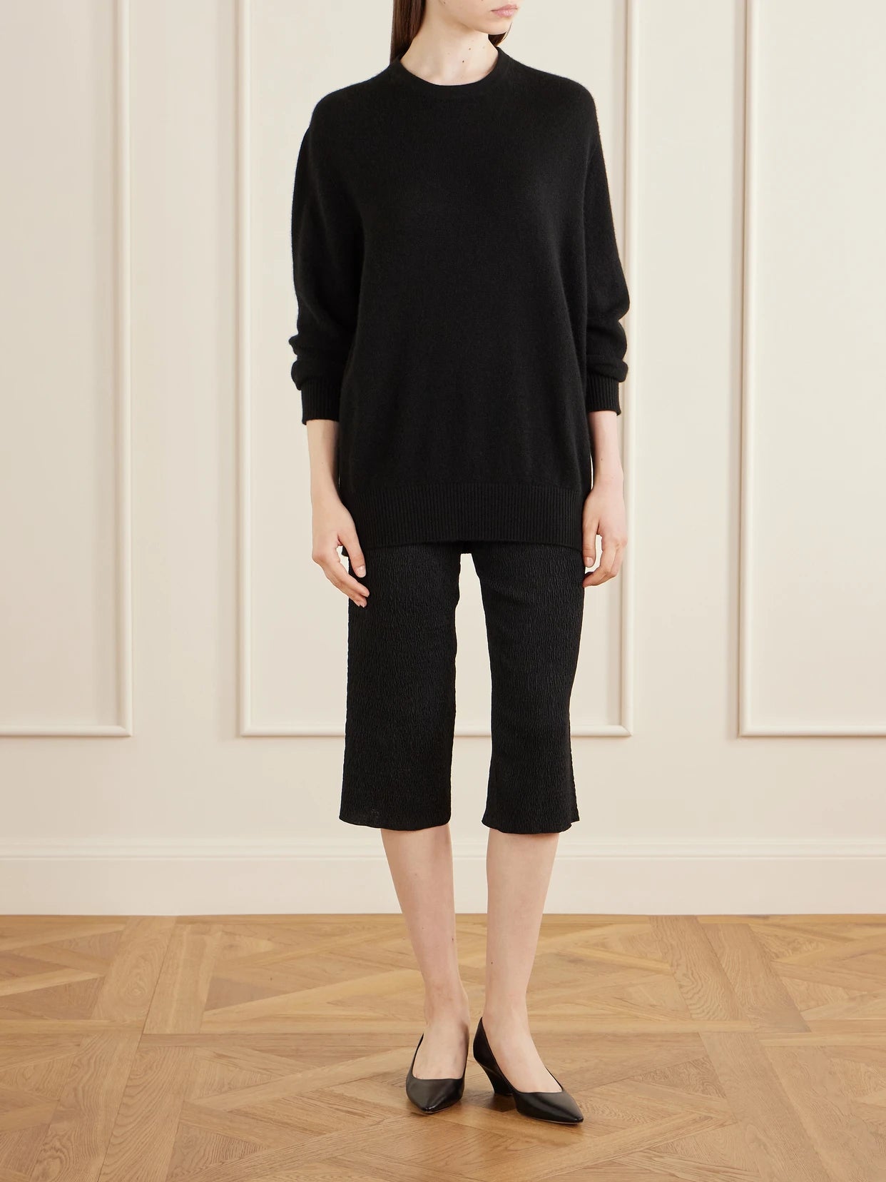 Image of a model wearing Shorts. Product name - Omero Silk Plissé Capris in Black colour by brand - The Row