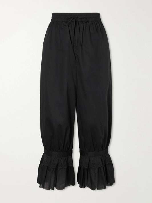 Image of a model wearing Pants. Product name - Renzo Cropped Scalloped Cotton-voile Balloon Pants in Black colour by brand - STAUD