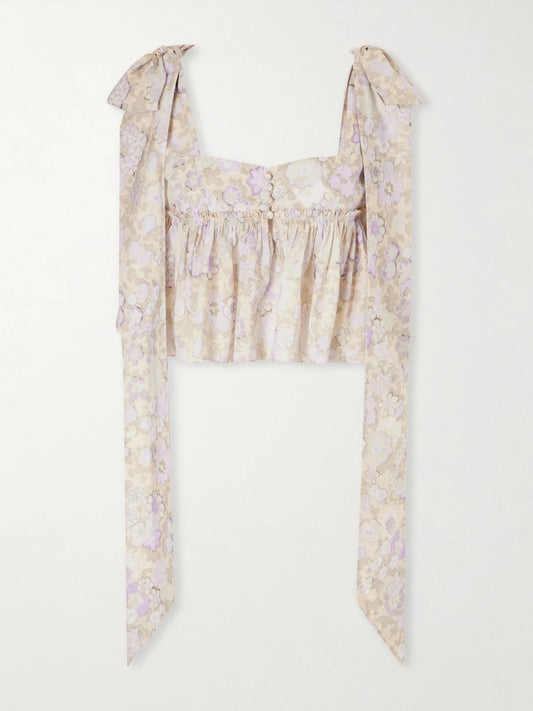 Image of a model wearing Tops. Product name - Bow-detailed Ruffled Floral-print Cotton-poplin Top in Purple colour by brand - Chloé