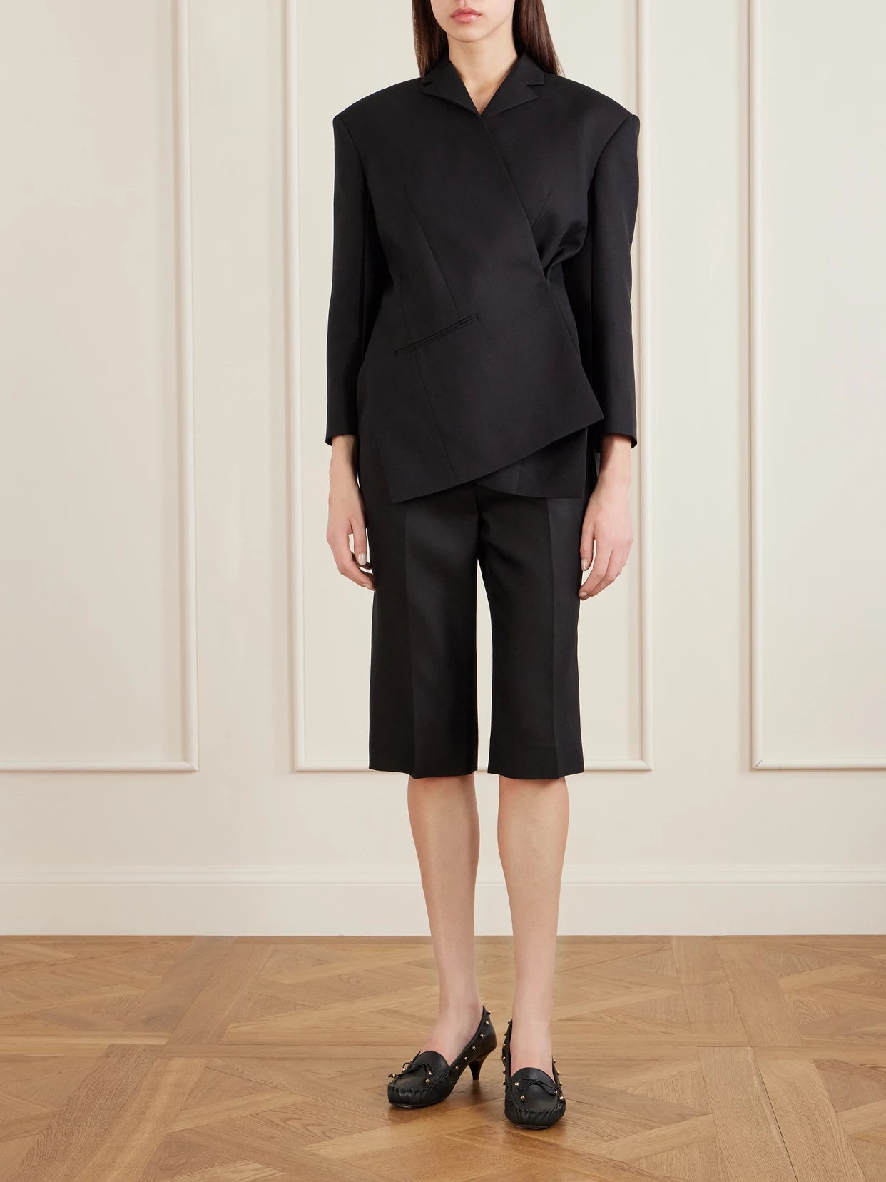 Image of a model wearing Shorts. Product name - Raelle Wool And Silk-blend Straight-leg Shorts in Black colour by brand - KHAITE
