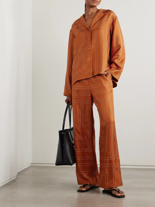 Image of a model wearing Pants. Product name - Embroidered Silk-twill Wide-leg Pants in Orange colour by brand - TOTEME