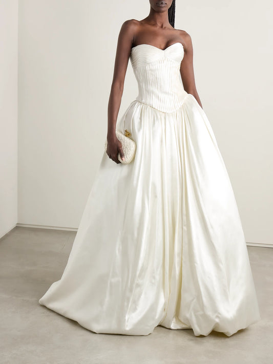 Image of a model wearing Tops. Product name - Ella Strapless Frayed Pintucked Silk And Wool-blend Satin Bustier Top in Off-white colour by brand - Danielle Frankel