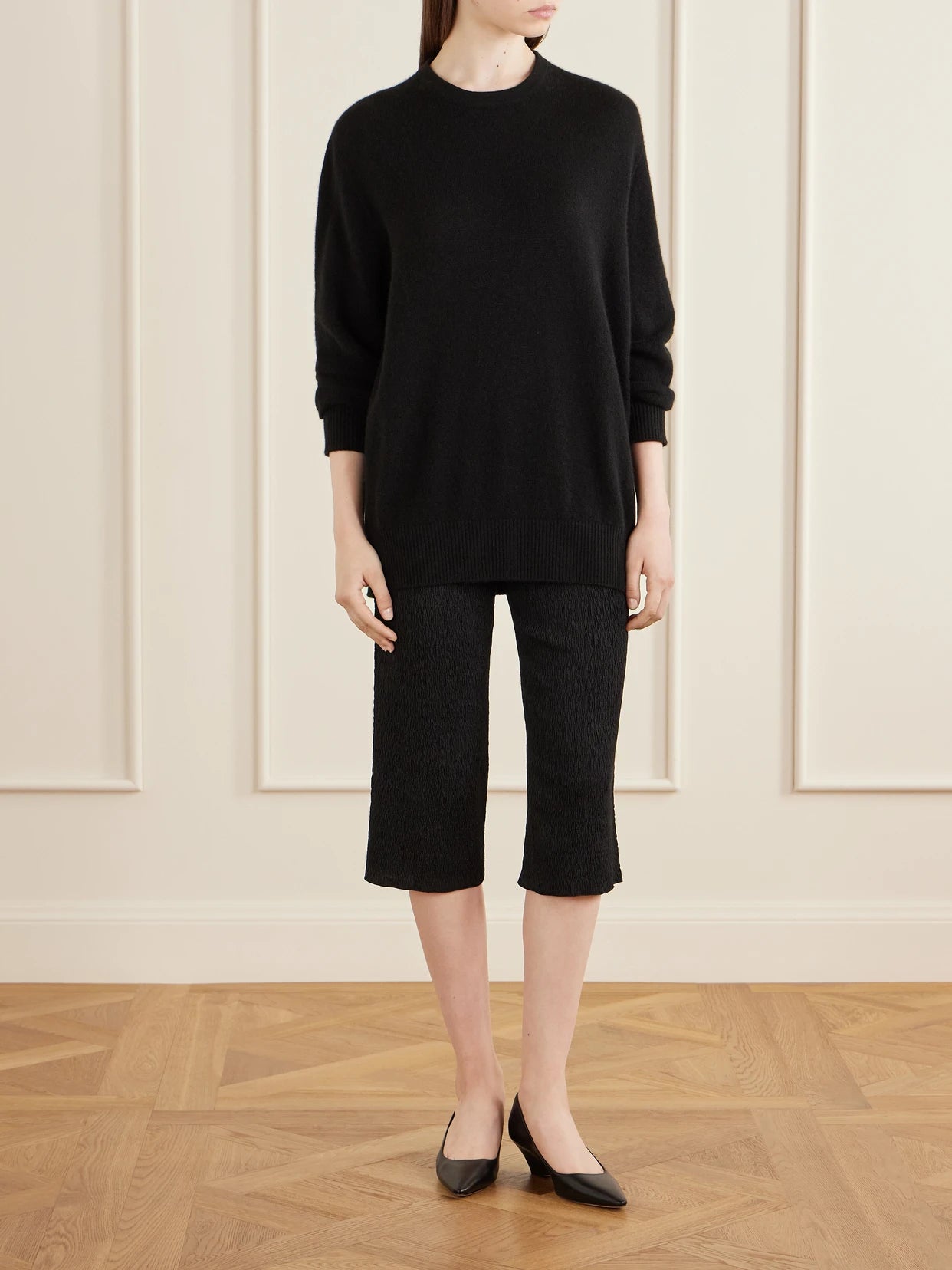 Image of a model wearing Outerwear. Product name - Odelle Cashmere Knit Sweater in Black colour by brand - The Row