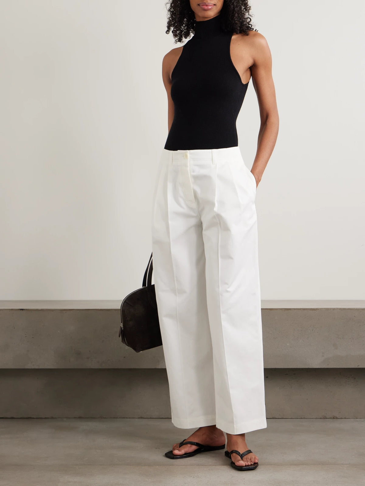 Image of a model wearing Pants. Product name - Pleated Cotton-twill Wide-leg Pants in White colour by brand - TOTEME