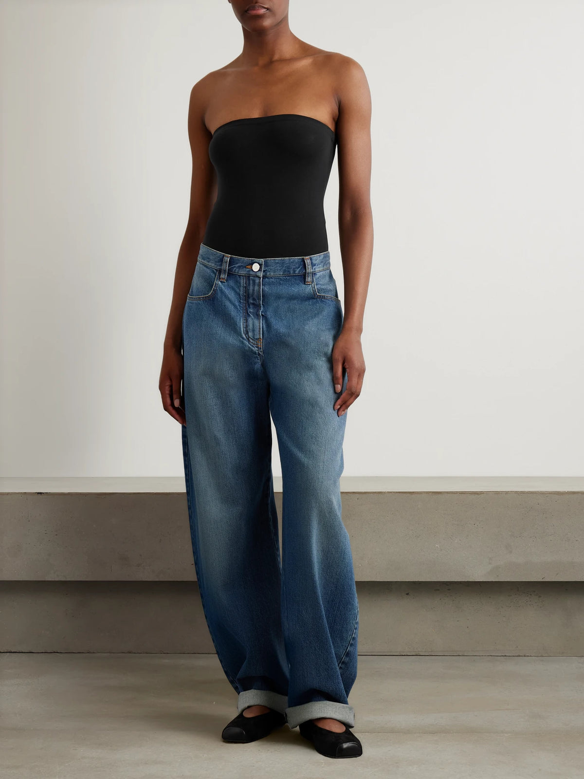 Image of a model wearing Tops. Product name - Strapless Stretch-jersey Bodysuit in Black colour by brand - Alaïa