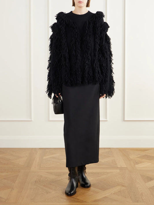 Image of a model wearing Outerwear. Product name - Kiri Fringed Cashmere Sweater in Black colour by brand - LISA YANG