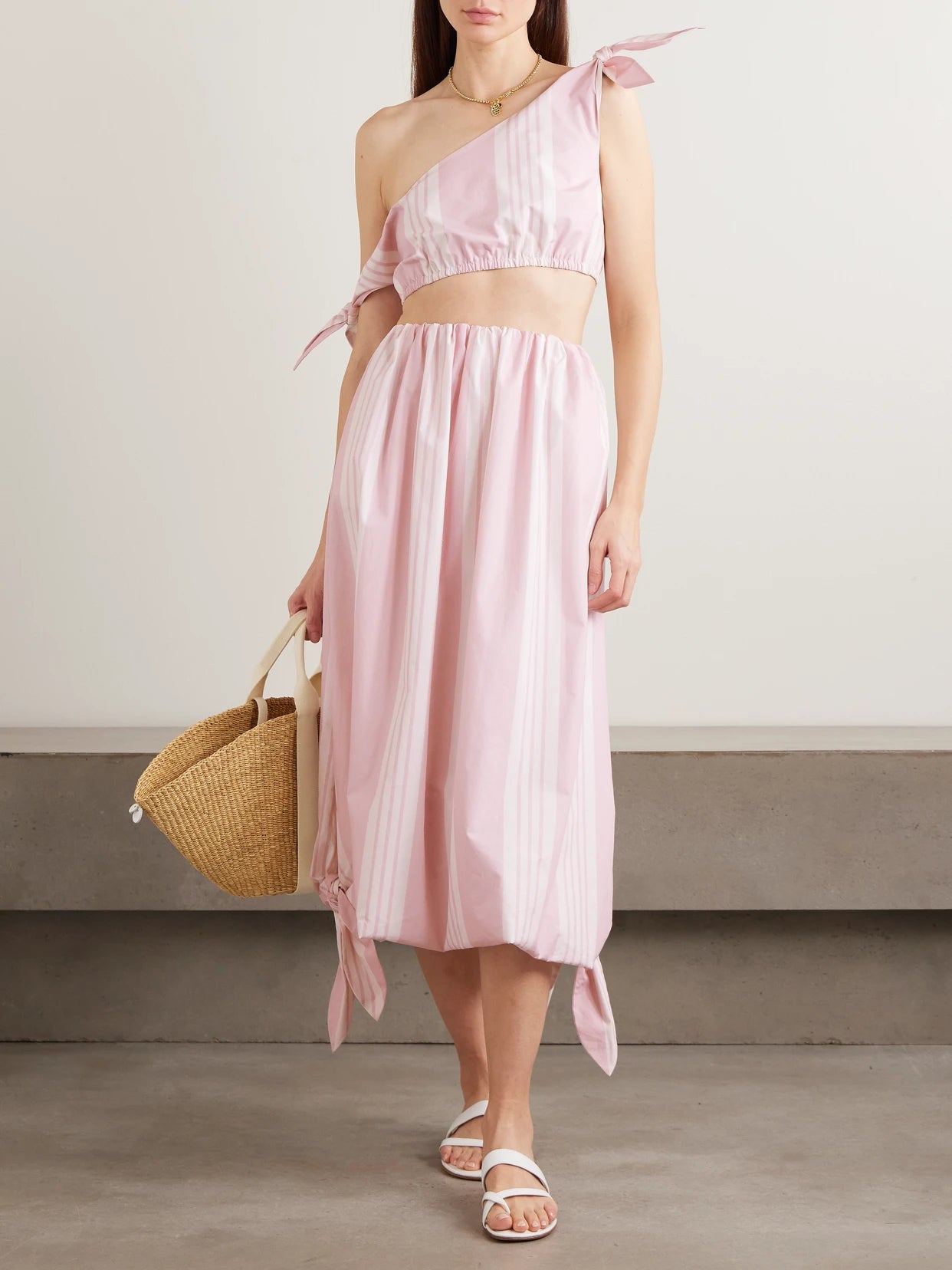 Image of a model wearing Skirts. Product name - Rose Tie-detailed Striped Cotton Midi Skirt in Pink colour by brand - Posse