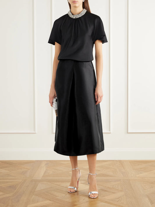 Image of a model wearing Skirts. Product name - Vexa Pleated Duchess-satin Midi Skirt in Black colour by brand - SIMKHAI