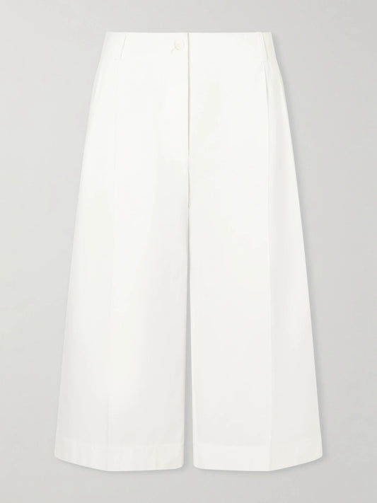 Image of a model wearing Pants. Product name - Cropped Pleated Organic Cotton And Lyocell-blend Straight-leg Pants in White colour by brand - TOTEME
