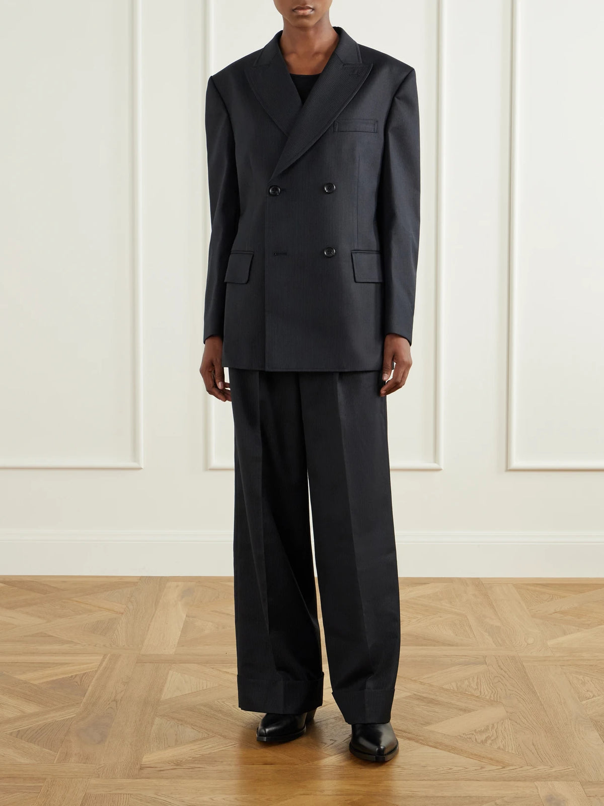 Image of a model wearing Pants. Product name - Pinstriped Wool-blend Wide-leg Pants in Black colour by brand - Junya Watanabe