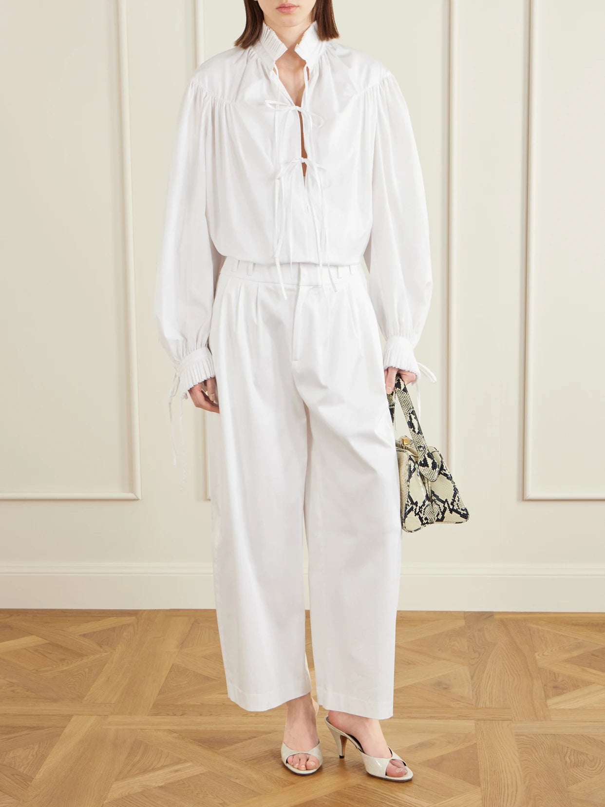 Image of a model wearing Pants. Product name - Wilson Pleated Cotton Wide-leg Pants in White colour by brand - Altuzarra