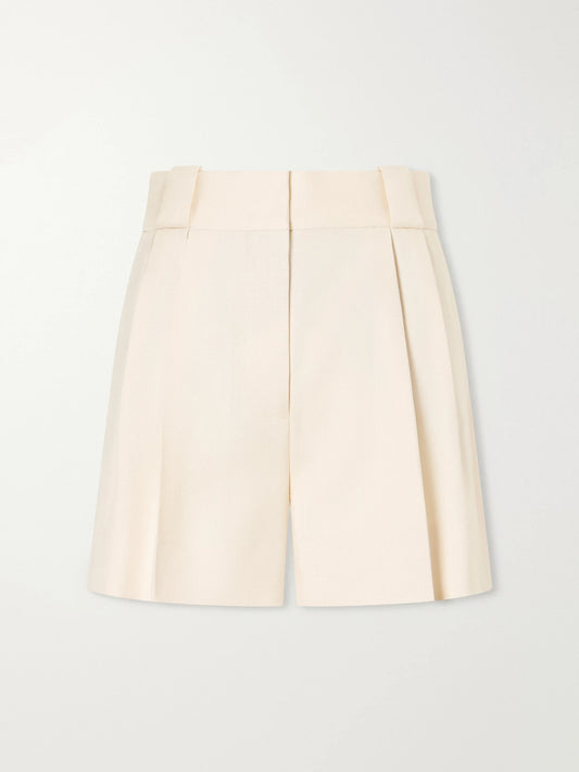 Image of a model wearing Shorts. Product name - Danae Mid-rise Pleated Canvas Shorts in Beige colour by brand - BLAZÉ Milano