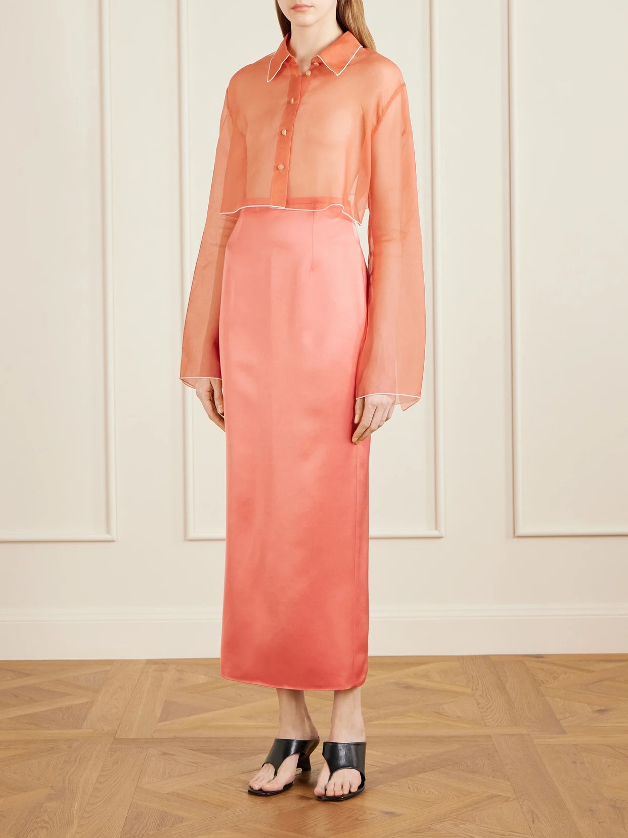 Image of a model wearing Skirts. Product name - Winton Satin Midi Skirt in Coral colour by brand - KHAITE