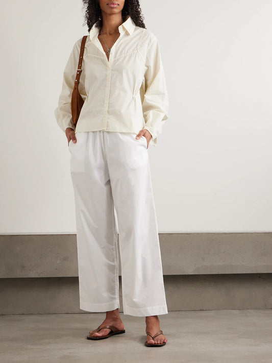 Image of a model wearing Tops. Product name - Cami Paneled Pintucked Striped Organic Cotton-poplin Shirt in Yellow colour by brand - Deiji Studios
