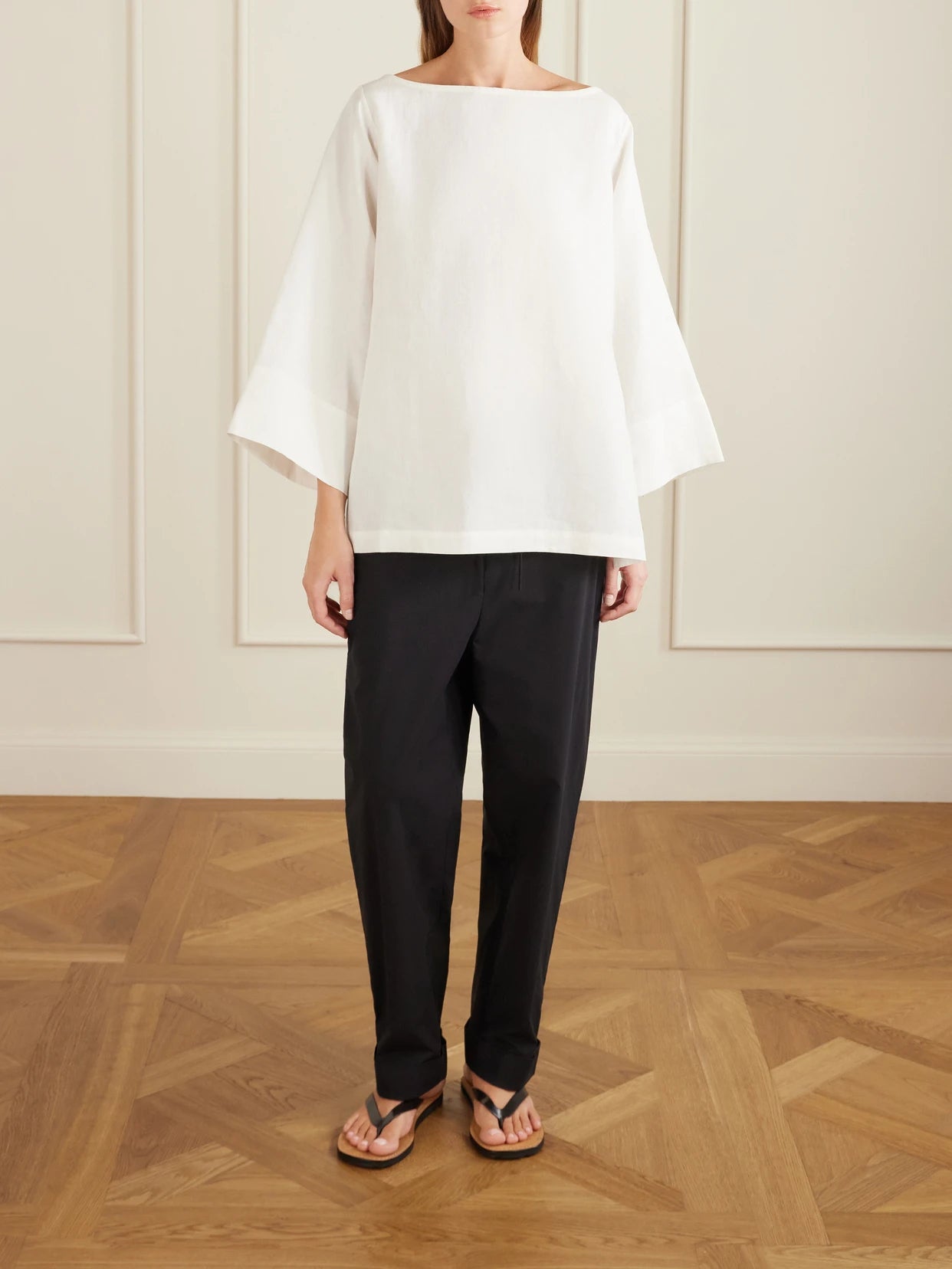 Image of a model wearing Pants. Product name - Delano Cropped Cotton Wide-leg Pants in Black colour by brand - The Row