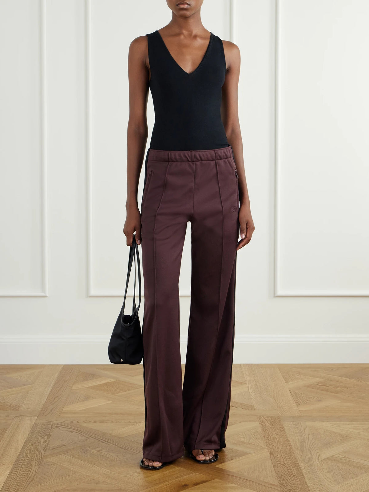 Image of a model wearing Pants. Product name - Cady Track Pants in Merlot colour by brand - COURREGES