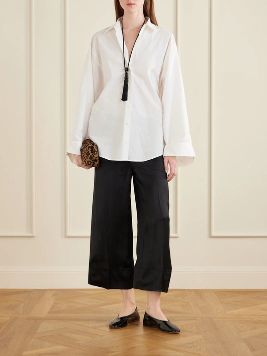 Image of a model wearing Pants. Product name - Drawstring Wide-leg Satin Pants in Black colour by brand - TOTEME