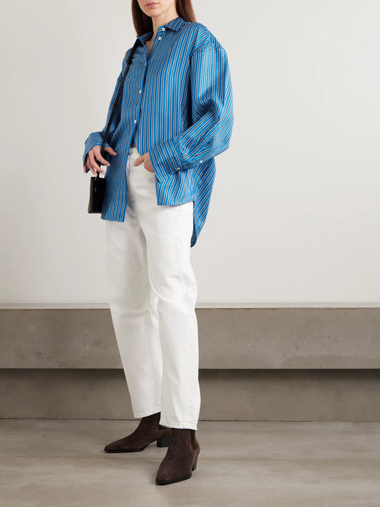 Image of a model wearing Tops. Product name - Oversized Striped Silk-twill Shirt in Blue colour by brand - TOTEME