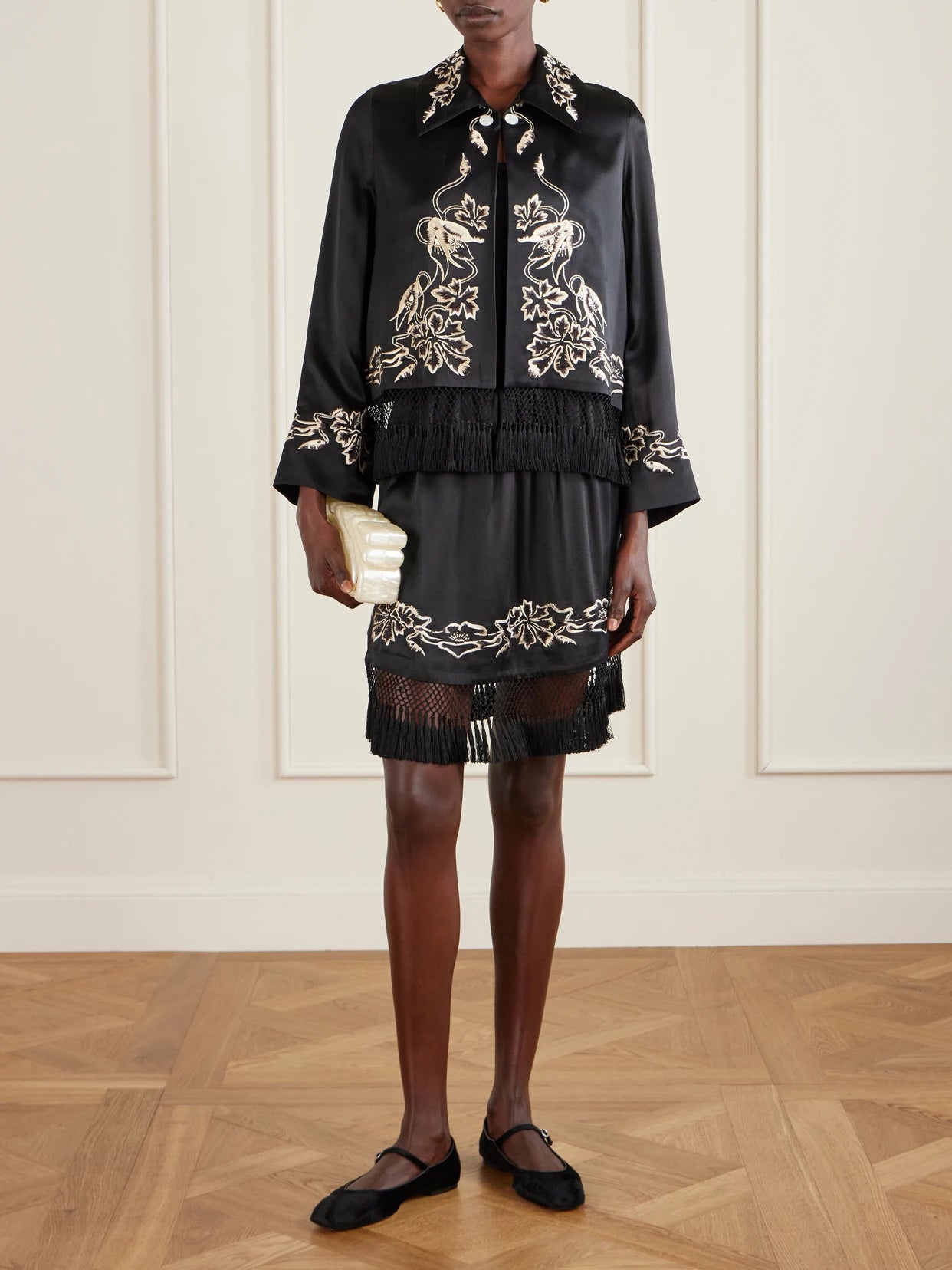 Image of a model wearing Skirts. Product name - Phantasm Fringed Embroidered Silk-satin Mini Skirt in Black colour by brand - BODE