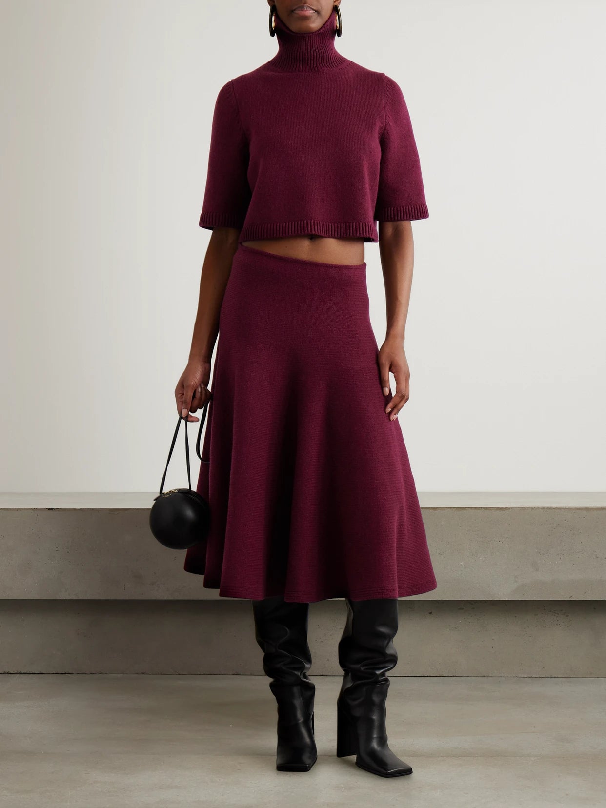 Image of a model wearing Skirts. Product name - Pleated Knitted Cashmere-blend Midi Skirt in Burgundy colour by brand - Alaïa