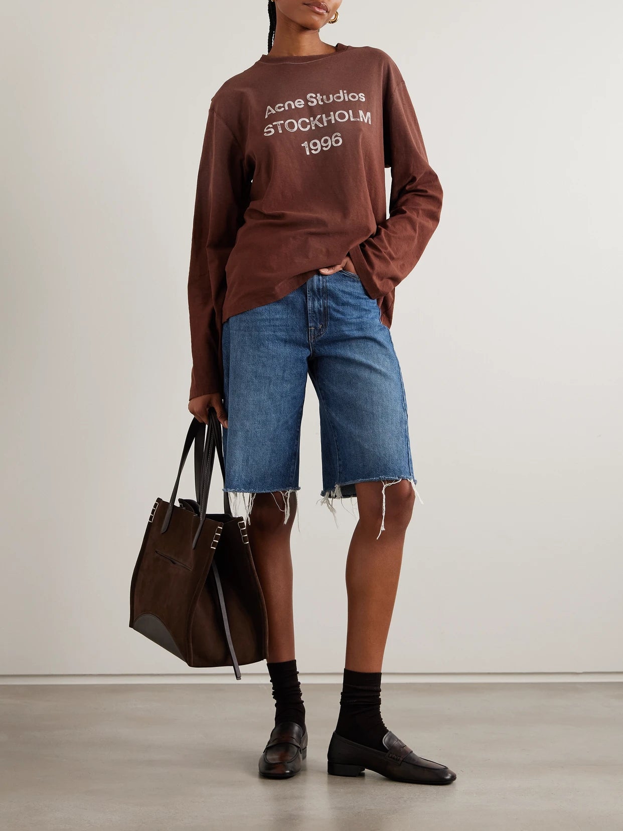 Image of a model wearing Shorts. Product name - The Half Pipe Bermuda Fray Denim Shorts in Mid denim colour by brand - Mother