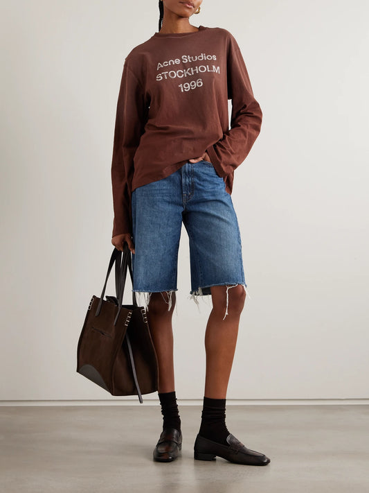 Image of a model wearing Shorts. Product name - The Half Pipe Bermuda Fray Denim Shorts in Mid denim colour by brand - Mother
