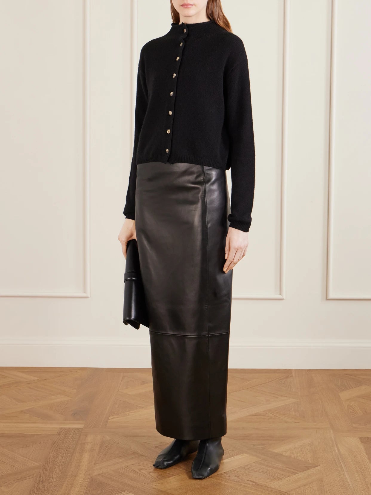Image of a model wearing Skirts. Product name - Lyle Leather Midi Skirt in Black colour by brand - KHAITE