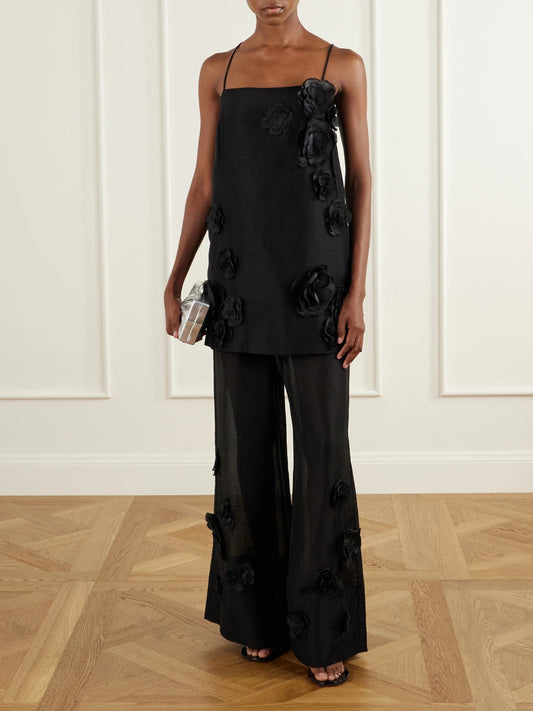 Image of a model wearing Pants. Product name - Cloudscape Flower-appliqué Lyocell And Linen-blend Mid-rise Wide-leg Pants in Black colour by brand - Aje