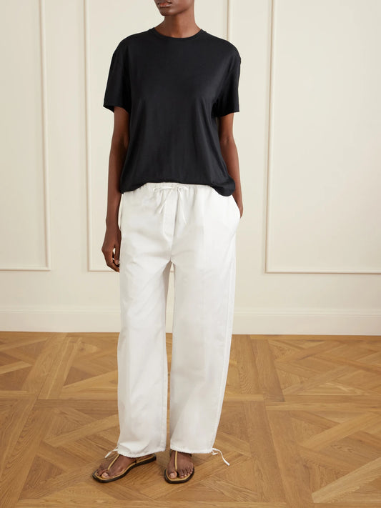 Image of a model wearing Pants. Product name - Cotton Wide-leg Drawstring Balloon Pants in White colour by brand - TOTEME