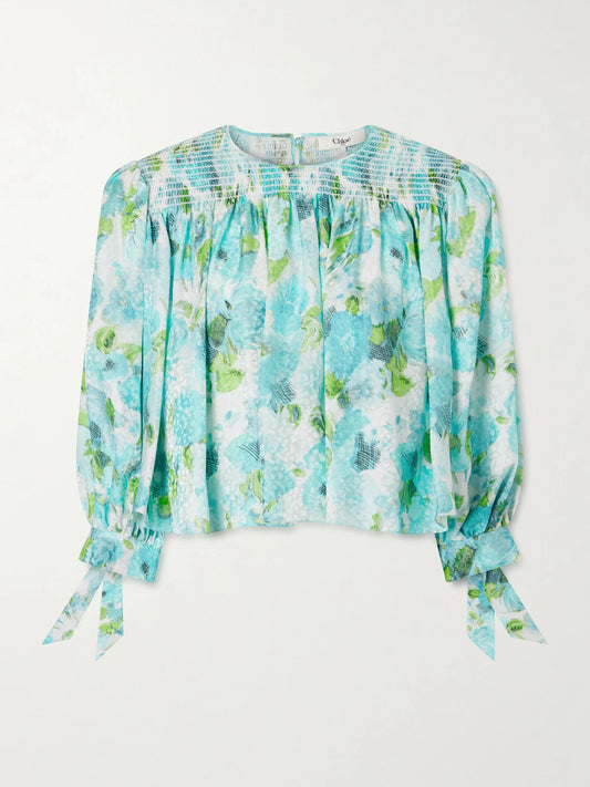 Image of a model wearing Tops. Product name - Cropped Smocked Floral-print Silk-jacquard Blouse in Blue colour by brand - Chloé