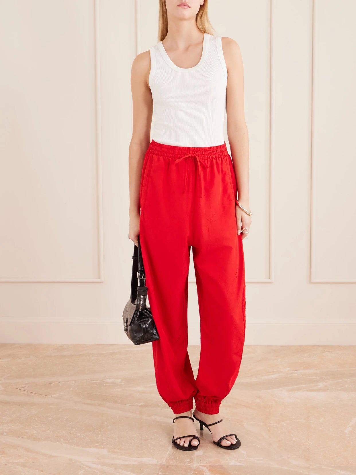 Image of a model wearing Pants. Product name - Crinkled Cotton-blend Balloon Pants in Red colour by brand - RÓHE