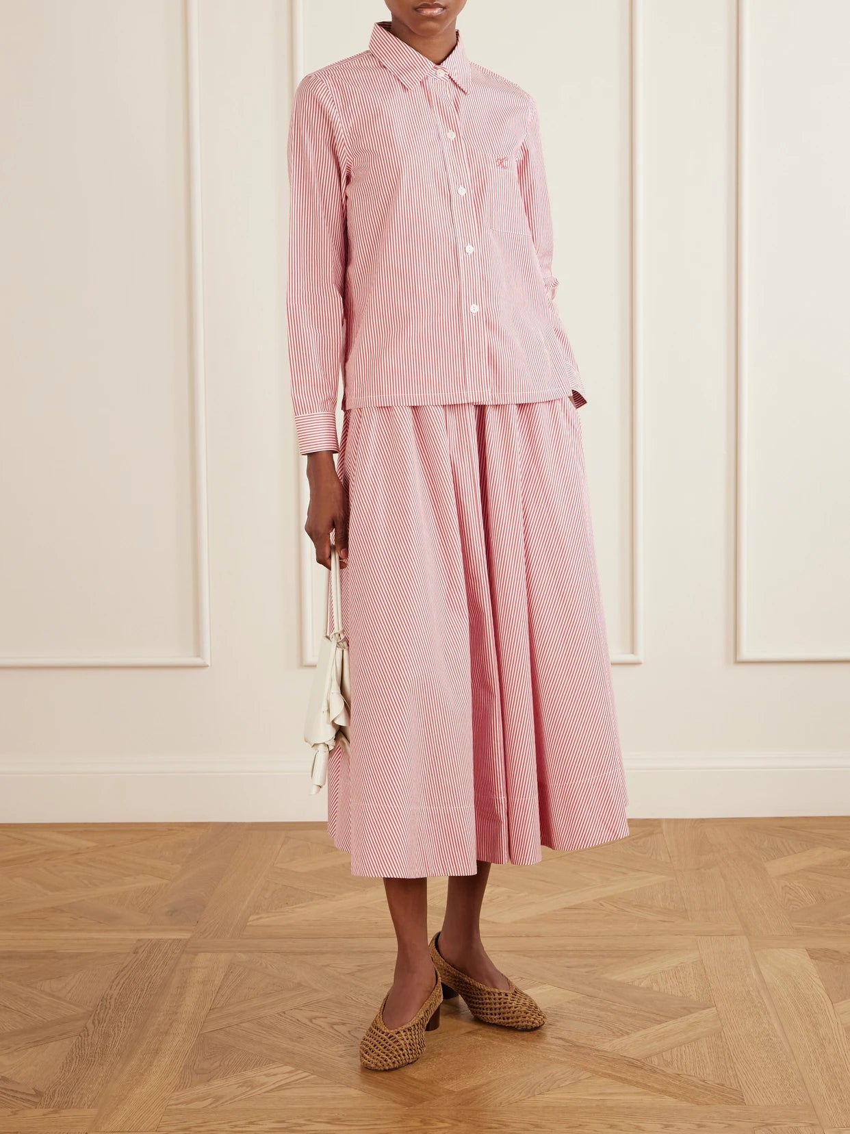 Image of a model wearing Skirts. Product name - Kyria Shirred Striped Cotton-poplin Midi Skirt in Pink colour by brand - Suzie Kondi