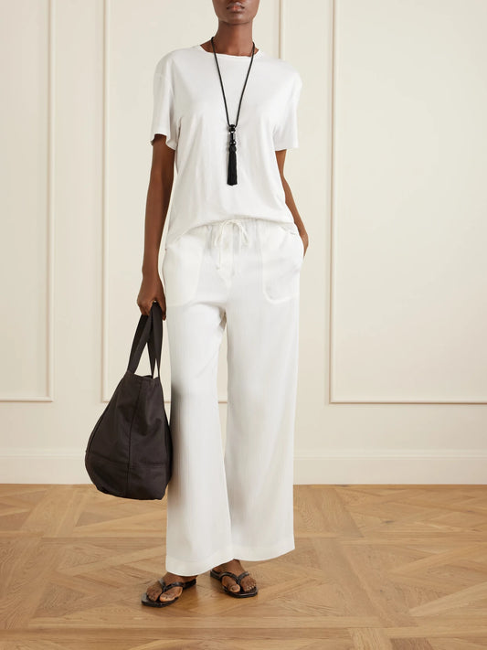 Image of a model wearing Pants. Product name - Striped Woven Wide-leg Pants in White colour by brand - TOTEME