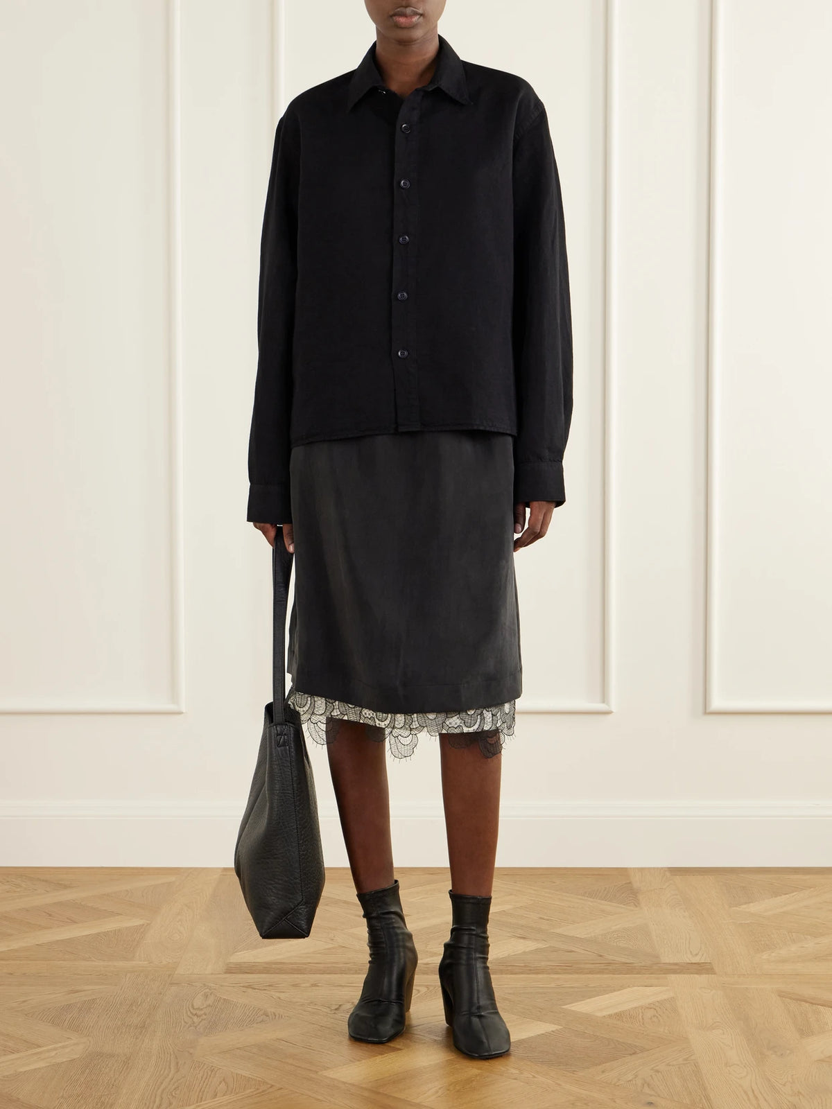 Image of a model wearing Skirts. Product name - Alder Lace-trimmed Lyocell-twill Knee Skirt in Black colour by brand - Studio Nicholson