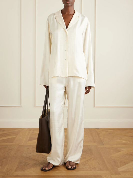 Image of a model wearing Pants. Product name - Monogram Silk Wide-leg Pyjama Pants in Cream colour by brand - TOTEME