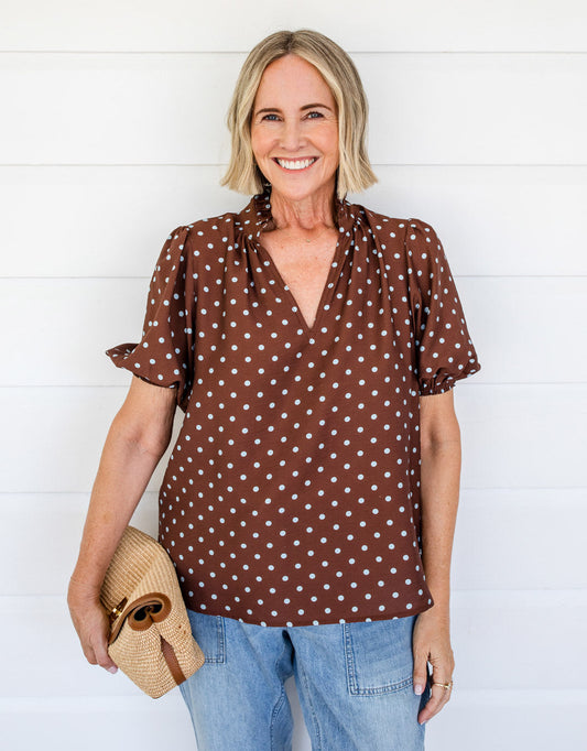 Image of a model wearing Tops. Product name - Ascot Ruffle Blouse Choc/Blue Polka Dot in Choc/Blue Polka Dot colour by brand - White & Co.