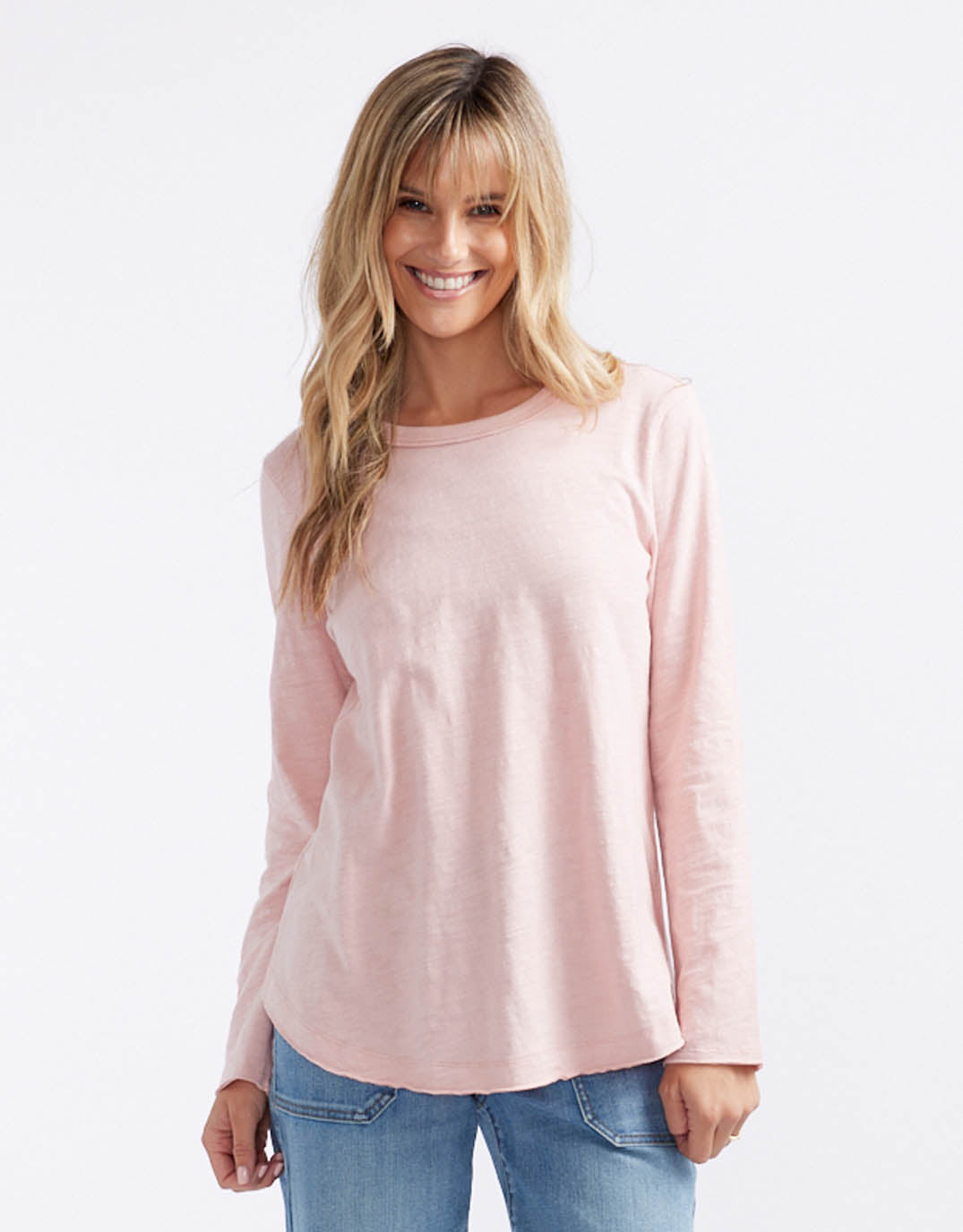 Image of a model wearing Tops. Productname: Essential Scoop Hem Long Sleeve T-shirt - in Dusty Rose colour by brand - White & Co.