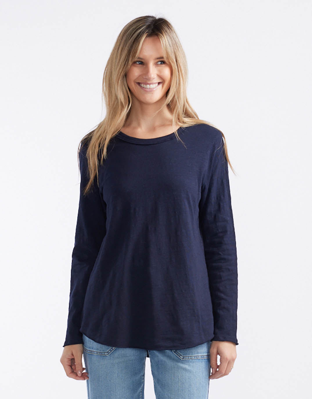 Image of a model wearing Tops. Productname: Essential Scoop Hem Long Sleeve T-shirt - in Navy colour by brand - White & Co.