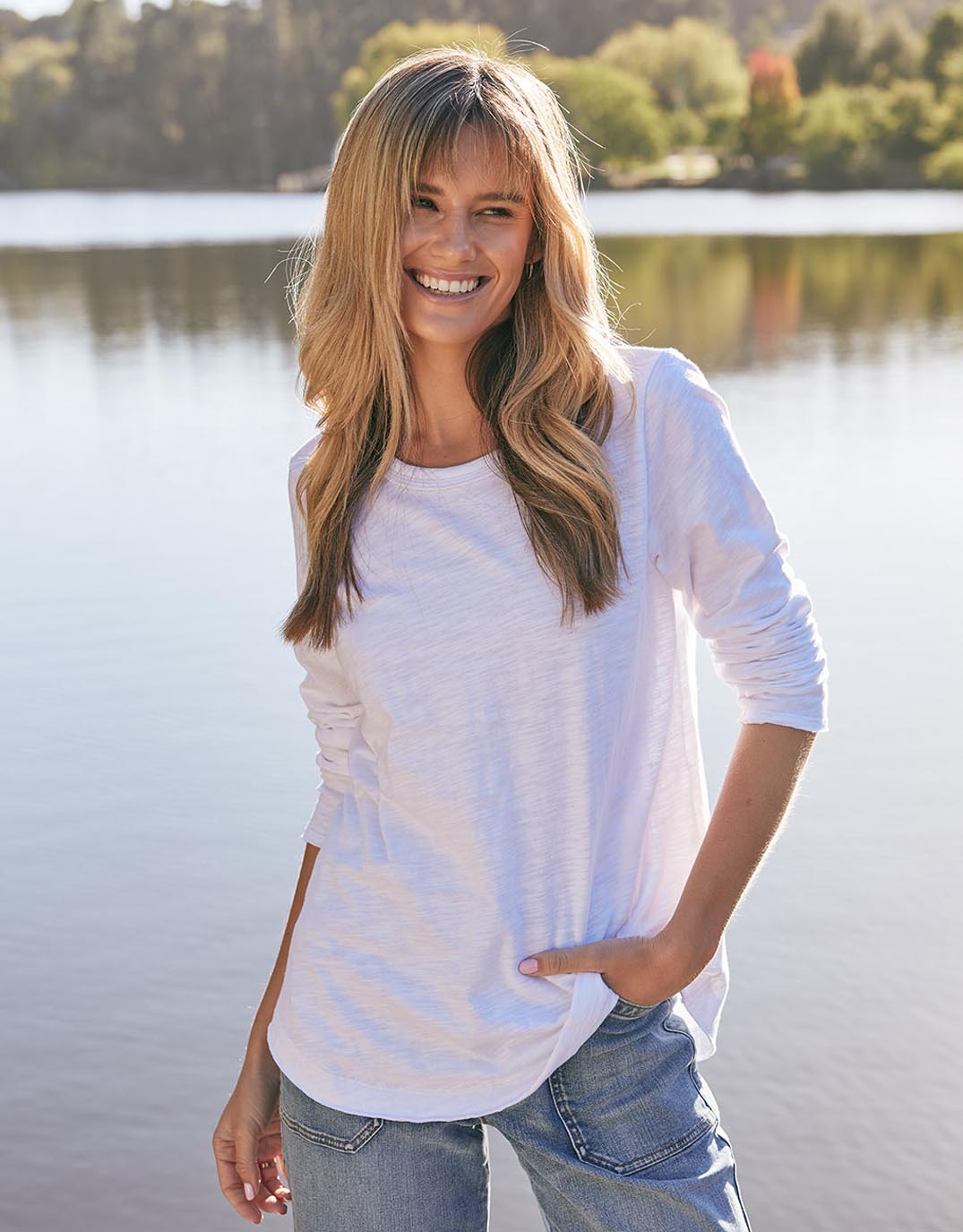 Image of a model wearing Tops. Productname: Essential Scoop Hem Long Sleeve T-shirt - in White colour by brand - White & Co.