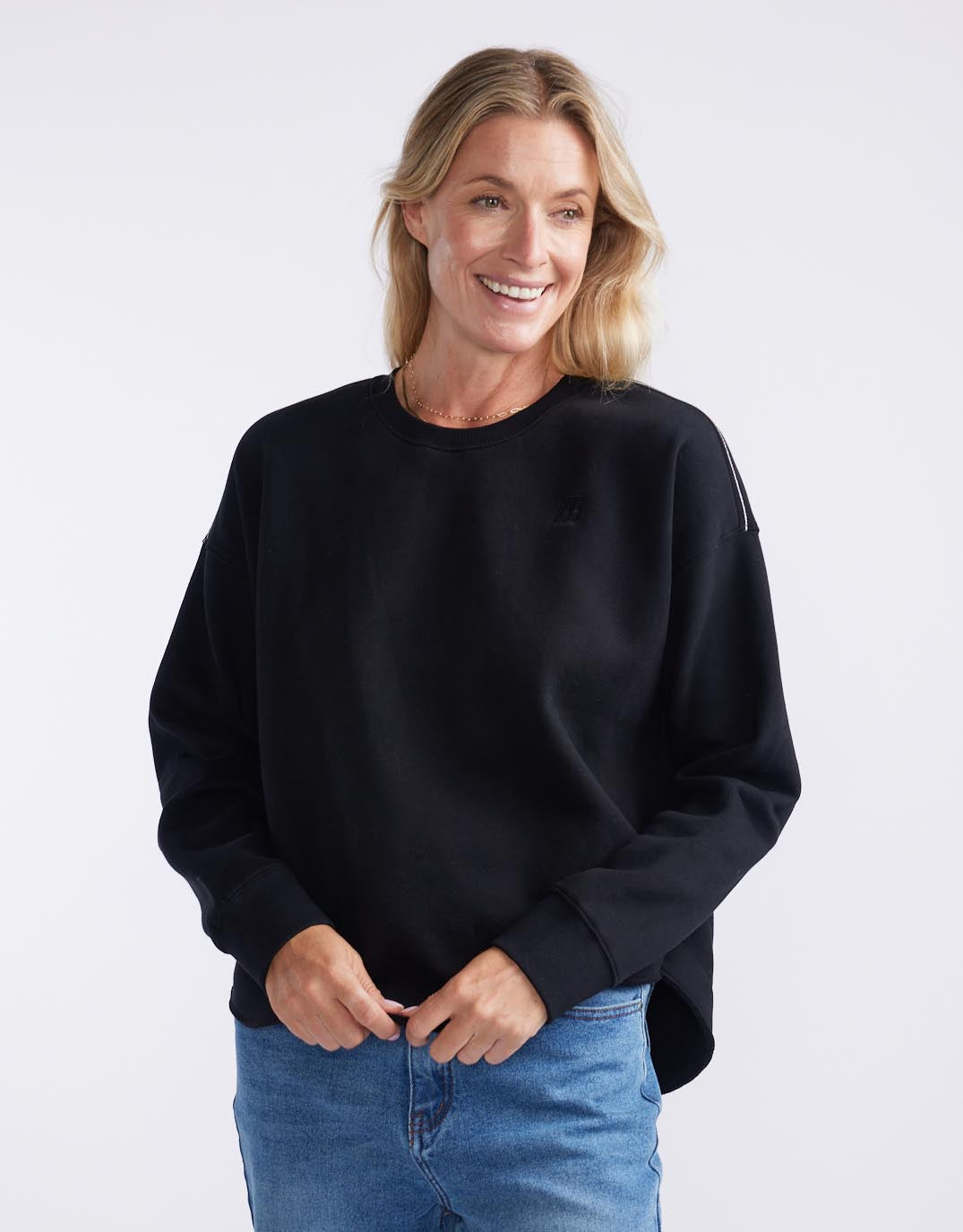 Image of a model wearing Tops. Productname: Monogram Fleece Scoop Hem Sweat - in Black colour by brand - White & Co.