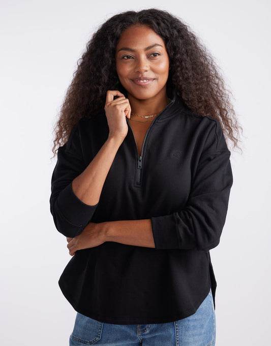 Image of a model wearing Outerwear. Productname: Unwind Half Zip Sweater - in Black colour by brand - White & Co.